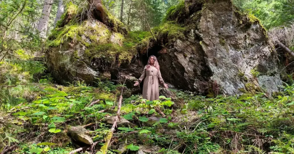Energetik, TCM, Bewusstsein Frau in Kleid steht zwischen zwei Felsen im Wald, als Symbol von Energetik, TCM und Bewusstsein